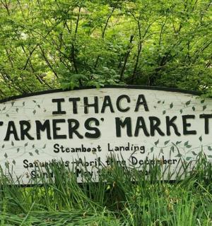 a sign for a farmers market in the grass
