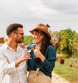 a man and woman drinking wine in an orchard