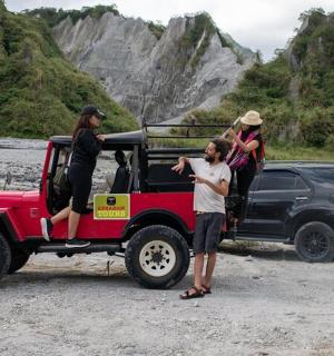 isang grupo ng mga tao na nakatayo sa likod ng isang jeep