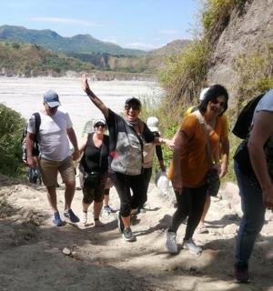 isang grupo ng mga tao na naglalakad sa isang trail malapit sa isang ilog