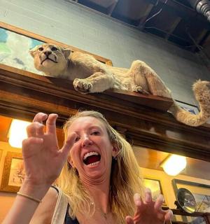 žena držící ruce před sochou lva