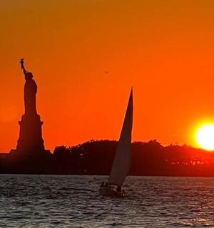 日落时分自由女神像前的一艘帆船