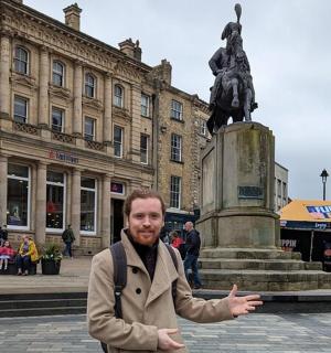 a man standing in front of a statue in a city