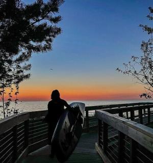 osoba držící surfovací prkno a dívající se na oceán