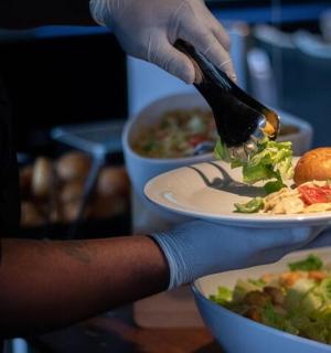 osoba držící talíř s jídlem s vidličkou a nožem