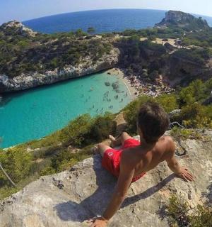 a young boy sitting on a rock overlooking a beach