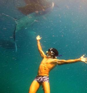 a young man standing in the water looking at a fish