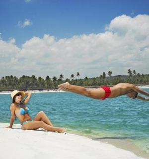 一男一女在海滩上，其中一名男子跳入水中