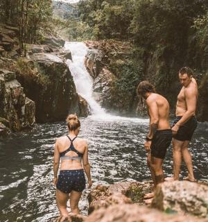 three people standing in the water near a waterfall