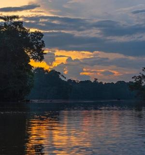 a sunset over a lake with trees in the background