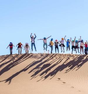 a group of people standing on top of a sand dune