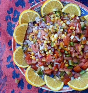 a plate of food with corn salsa and orange slices