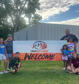 a group of people posing in front of a welcome sign