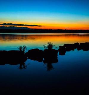 a sunset over a lake with rocks in the water