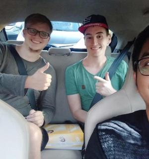 three men sitting in a car giving thumbs up