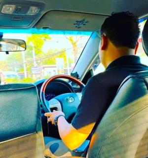 a man driving a car with a surfboard on the dashboard