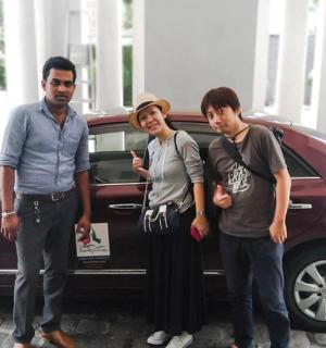 a group of three people standing in front of a car