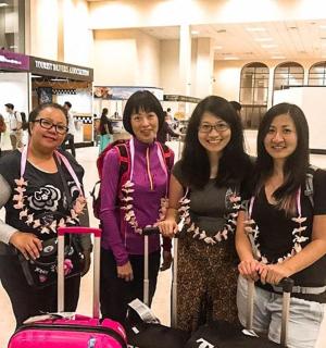four women posing for a picture at an airport