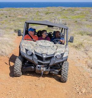 一群人坐在吉普车上,行驶在土路上