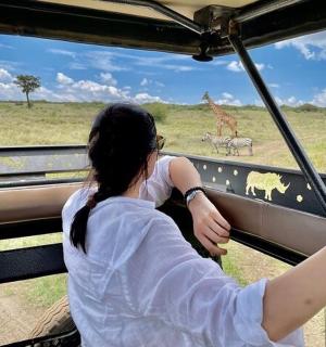 a woman looking out a window at a giraffe