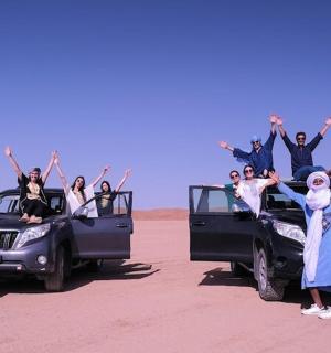 a group of people sitting on the back of their cars in the desert