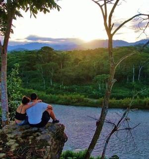a man and a woman sitting on a rock near a river