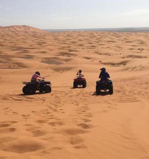 三个人骑着四轮摩托车在沙漠中穿行