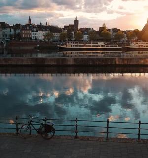 a bike parked next to a fence next to a body of water