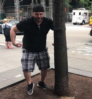 a man is standing next to a tree