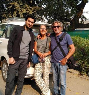 two men and a woman standing in front of a car