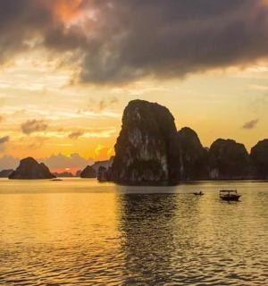 a boat in the water at sunset with rocks in the water