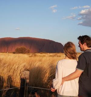 Pár stojící na poli s Ayers Rockem