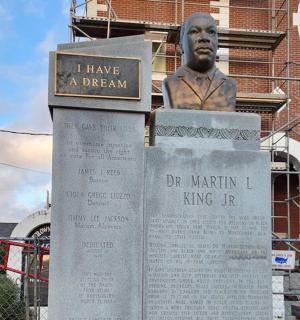 socha muže sedícího na vrcholu cedule