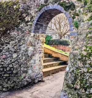 an archway in a stone wall with a staircase