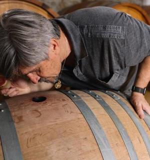 muž naklánějící se nad sud s hlavou na něm