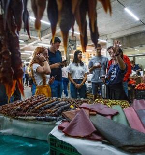a group of people standing around a market with meat