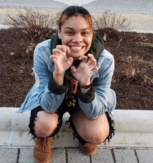 mladá žena klečící na obrubníku pózuje pro fotografii