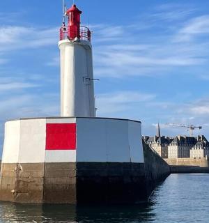 一座灯塔坐落在建筑物旁边的水中