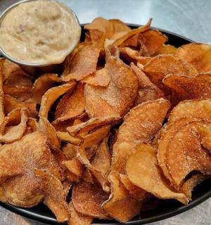 a plate of potato chips with a dipping sauce