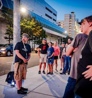 a group of people standing on a sidewalk near a street