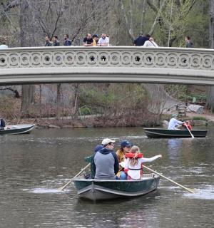 a group of people in boats on the water under a bridge