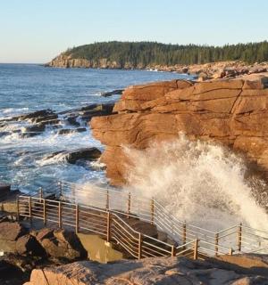 海浪冲击着岩石海岸线，旁边还有木制楼梯