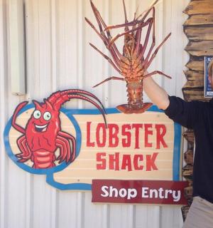 muž stojící před cedulí s humry