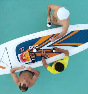 Dos personas están de pie junto a una tabla de surf.