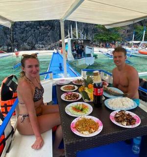 a man and a woman sitting at a table with food on a boat
