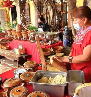 一位戴着口罩的女士站在摆着食物的桌子旁边