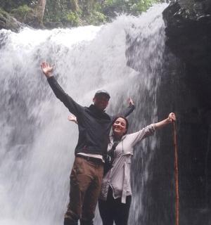 a man and a woman standing in front of a waterfall