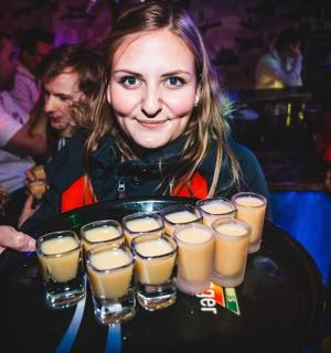 一位女士端着托盘,上面放着十二杯啤酒