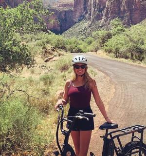 一名女子站在路边的一辆自行车旁