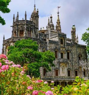 an old castle with pink flowers in front of it